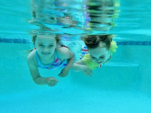 Two children swimming side by side underwater.