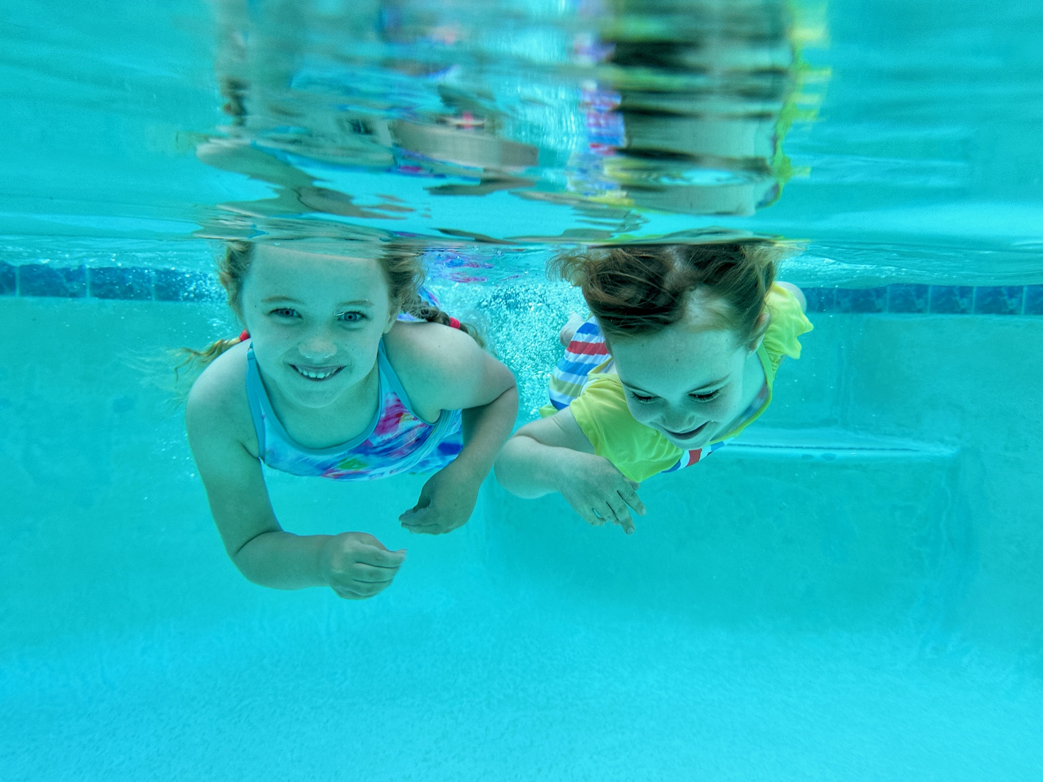 Two children swimming side by side underwater.
